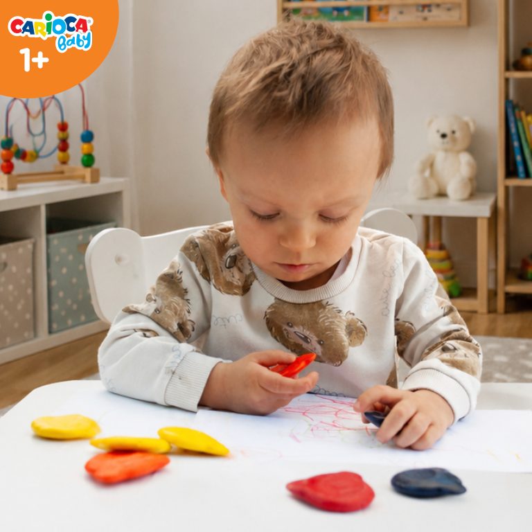 Roczne dziecko trzymające kredkę Carioca Baby sprawdza jej powierzchnię z wypustkami ułatwiającymi chwyt