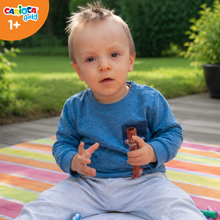 Roczne dziecko bawiące się pisakami Misiakami Carioca Baby siedzące na kocyku w ogrodzie.